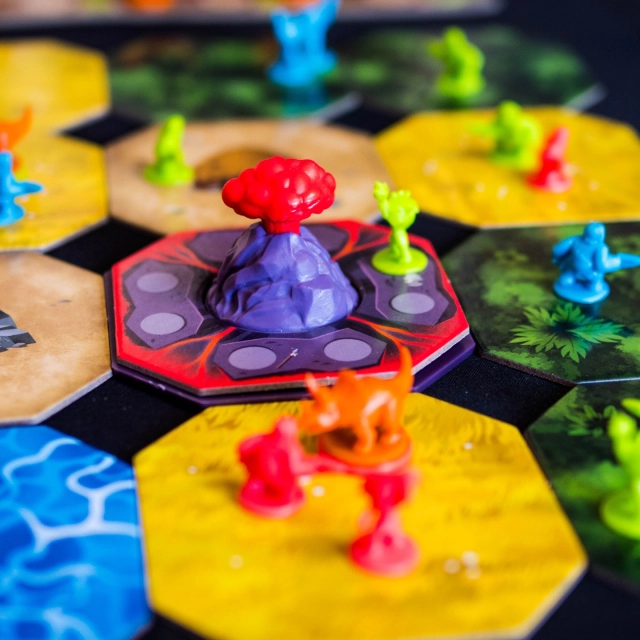 🔸La Colère de la Montagne de Feu🔸
(Fr & En)

@iello_fr

👀 Comment on joue ?

La Colère de la Montagne de Feu est un jeu de société familial de 2 à 4 joueurs, édité par Iello, dans lequel chaque joueur incarne une tribu préhistorique cherchant à dominer un territoire primitif en mutation avant que le volcan actif n’entre en éruption.

Chaque tour de jeu comprend plusieurs phases principales, simples à suivre mais riches en décisions :

1. Lancer les dés :
Au début de ton tour, tu lances les dés pour obtenir des combinaisons de symboles. Chaque symbole te permet d’effectuer une action différente.

2. Résoudre les résultats des dés : 
- Pour chaque symbole volcan, place un membre de ta tribu sur la tuile volcan.
- Pour chaque œuf, place un membre dans une zone d’éclosion.
- Pour chaque grotte ou hutte, place un pion sur la tuile correspondante de la grille 4×4.
- Pour chaque symbole pied, déplace l’un de tes personnages d’une case, en traversant éventuellement l’eau (mais sans t’y arrêter) et en évitant le volcan comme une zone infranchissable.

3. Faire éclore des dinosaures :
Si tu as assez de personnages dans une zone d’éclosion, tu peux prendre un dinosaure et l’ajouter à ta réserve. Les dinosaures disposent de pouvoirs spéciaux (dé supplémentaire, occuper l’eau, téléporter, etc.) qui enrichissent tes options stratégiques.

4. Dominer le volcan :
Si tu contrôles suffisamment de personnages sur la tuile volcan, tu peux déclencher un glissement de terrain, en poussant une ligne ou une colonne de tuiles, ce qui modifie le plateau et perturbe la stratégie des adversaires.

5. Éruption volcanique :
Lorsque toutes les cases volcaniques sont occupées, le volcan entre en éruption : on effectue un comptage de points par zone (jungle, herbe, eau), puis on remet les pièces utilisées dans les réserves. Si un joueur atteint le seuil de points requis, la partie se termine et celui qui a le plus de points gagne.
.
.
.
.
.
Copie presse